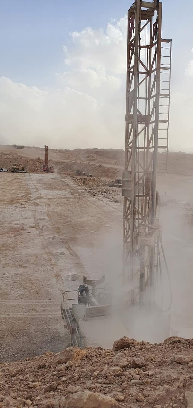 Drilling rig operating in dust cloud at phosphate extraction site, Jordan